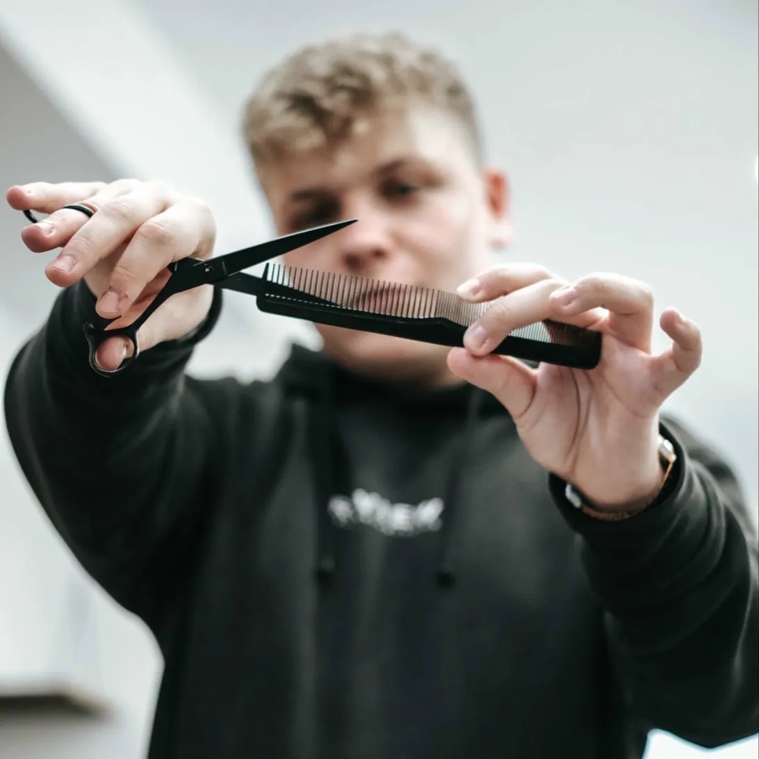 Barber THE ONE Barbershop Wadowice trzymający nożyczki